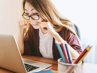 femme tendue mordant un crayon devant un ordinateur