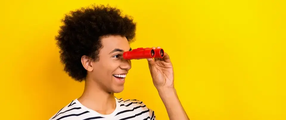 Un jeune homme souriant et regardant dans des jumelles