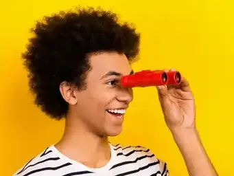 Un jeune homme souriant et regardant dans des jumelles